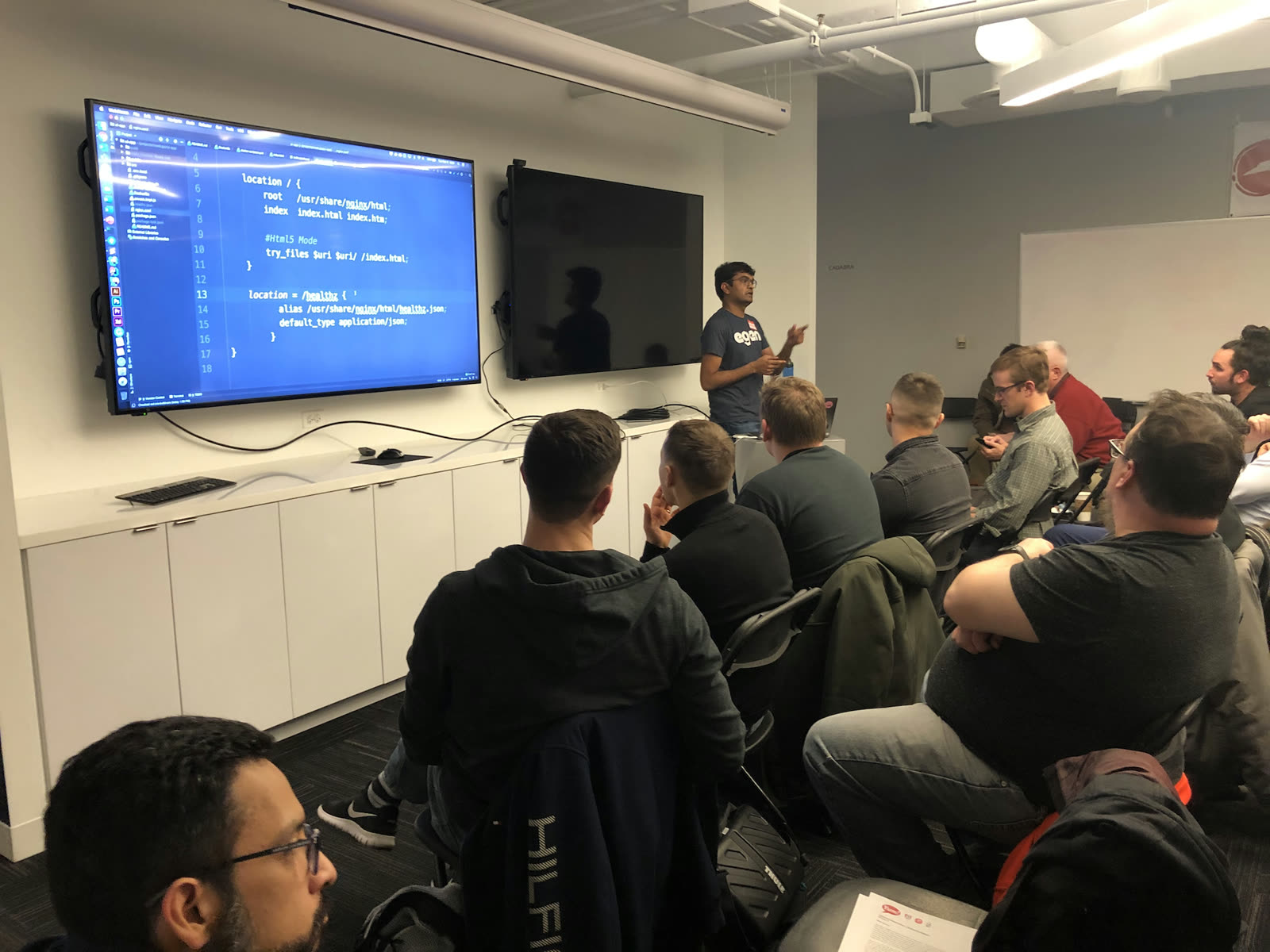 Presenting 12 Factor App principles for front-end apps to a seated meetup audience, an nginx configuration on the screen behind